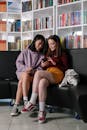 Two Teenagers Sitting on a Couch Looking at a Smartphone