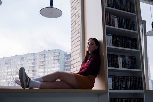 Female Teenager Sitting by the Window of the Library