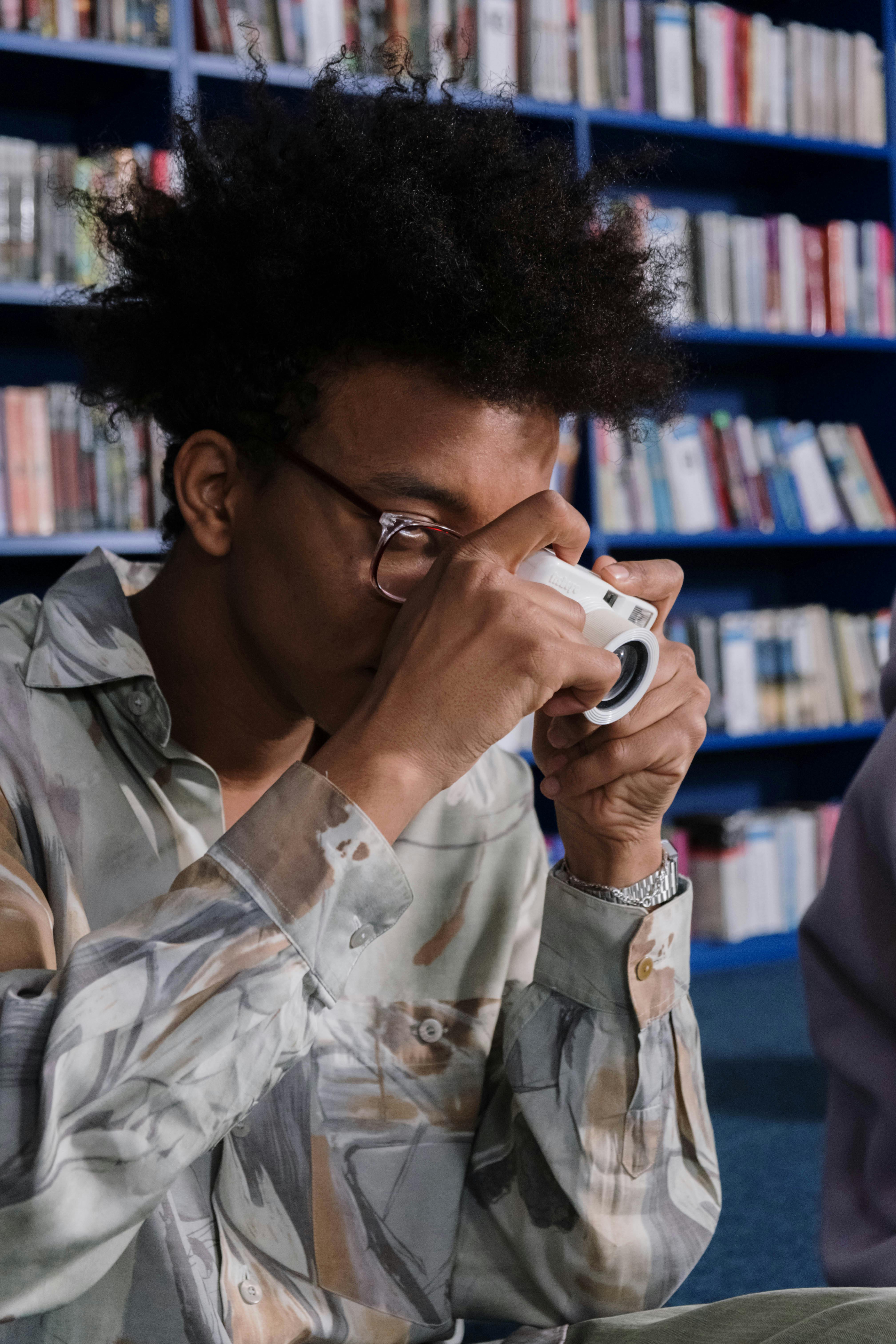 a male teenager with afro hair taking photos using a camera