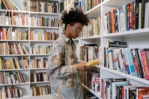 An Afro-Haired Man Reading a Book in the Library