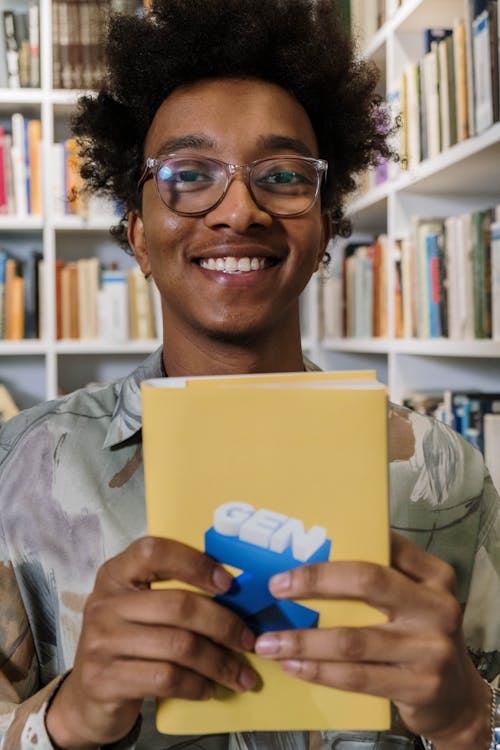 Free Close-Up Shot of an Afro-Haired Man Holding a Yellow Book Stock Photo