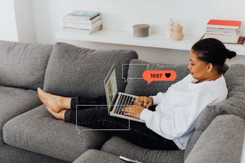Free A Woman in White Long Sleeves Sitting on a Sofa while Using a Laptop Stock Photo