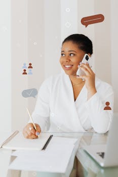 African American woman in office attire multitasking with phone and notepad.