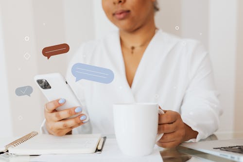 Close-Up Shot of a Person Using a Smartphone while Holding a Cup of Coffee