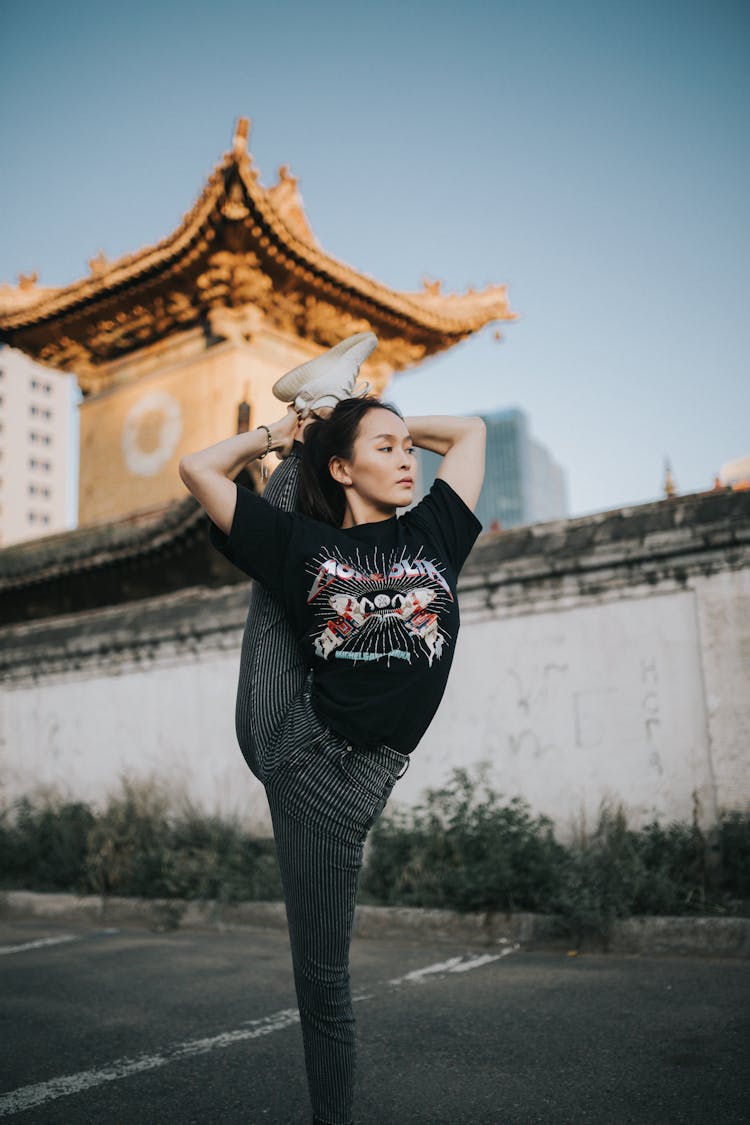 A Woman In Black Shirt Stretching Outside