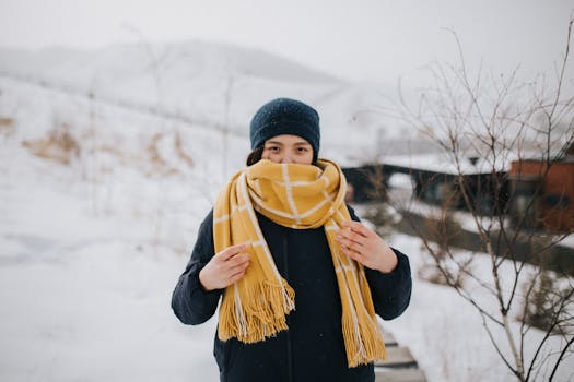 A woman wrapped in a warm scarf stands outdoors in a snowy Mongolian winter scene, showcasing cold weather fashion.