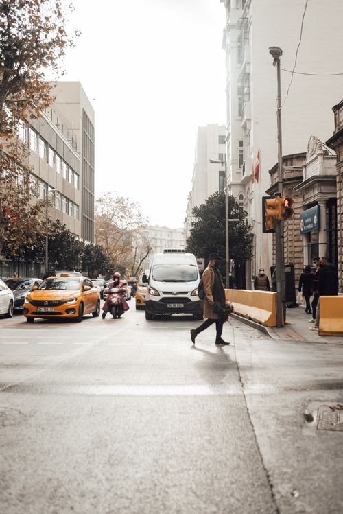 Free Male pedestrian in mask crossing asphalt road on busy street with cars stopped at red traffic light Stock Photo