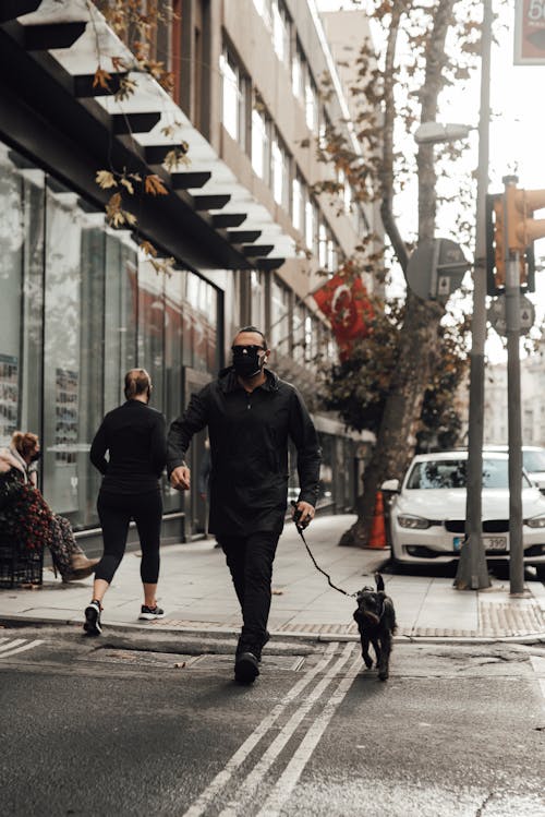 People walking along sidewalk near building in city