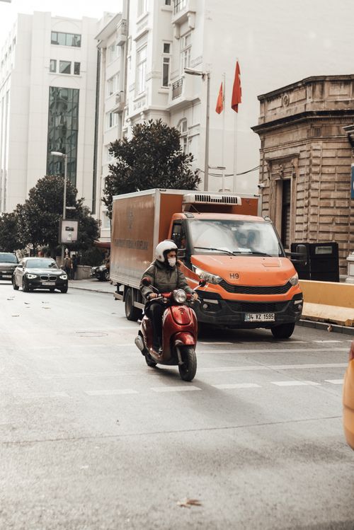 Free Male rider in helmet and protective mask riding motorcycle near vehicles along asphalt road with marking lines Stock Photo