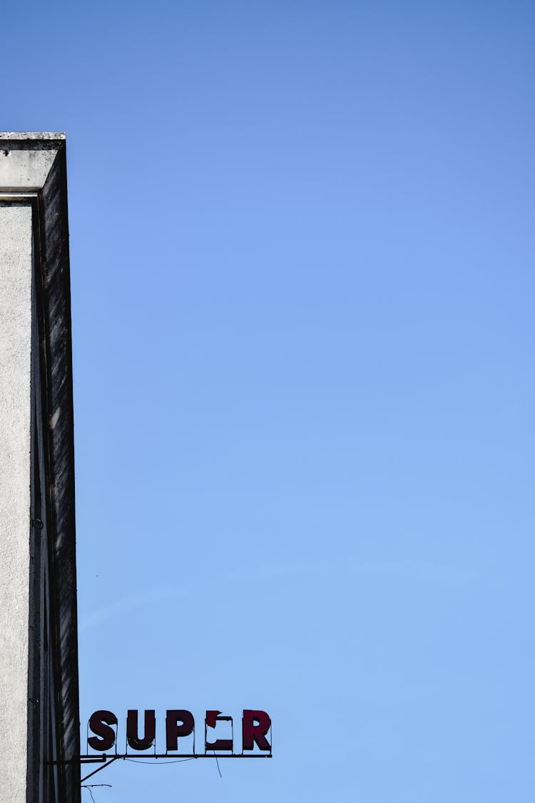 A Broken Sign Against The Blue Sky