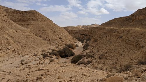 Free Explore a breathtaking view of an arid desert landscape with rocky terrain and sparse vegetation under a cloudy sky. Stock Photo