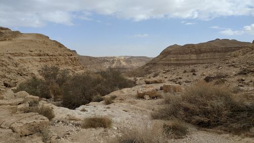 Free Breathtaking view of a rocky desert landscape featuring shrubs under a cloudy sky. Stock Photo
