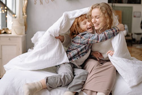 Free A Mother and Daughter Smiling while Under a Blanket Stock Photo