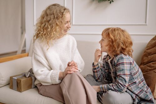 Free Warm moment between mother and daughter sharing happiness on a sofa. Stock Photo
