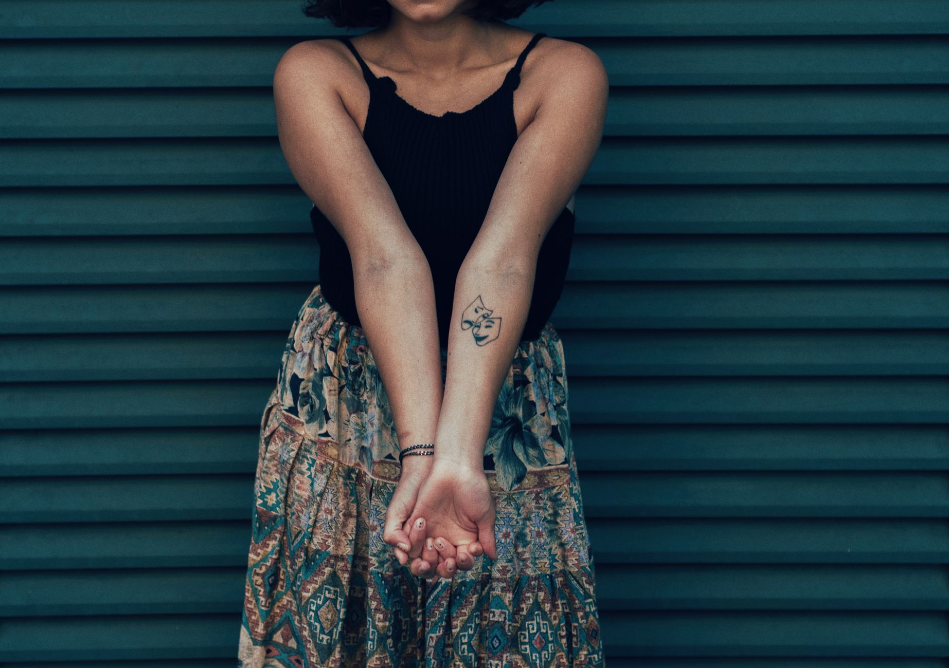 Woman showing a small delicate wrist tattoo, styled for everyday wear