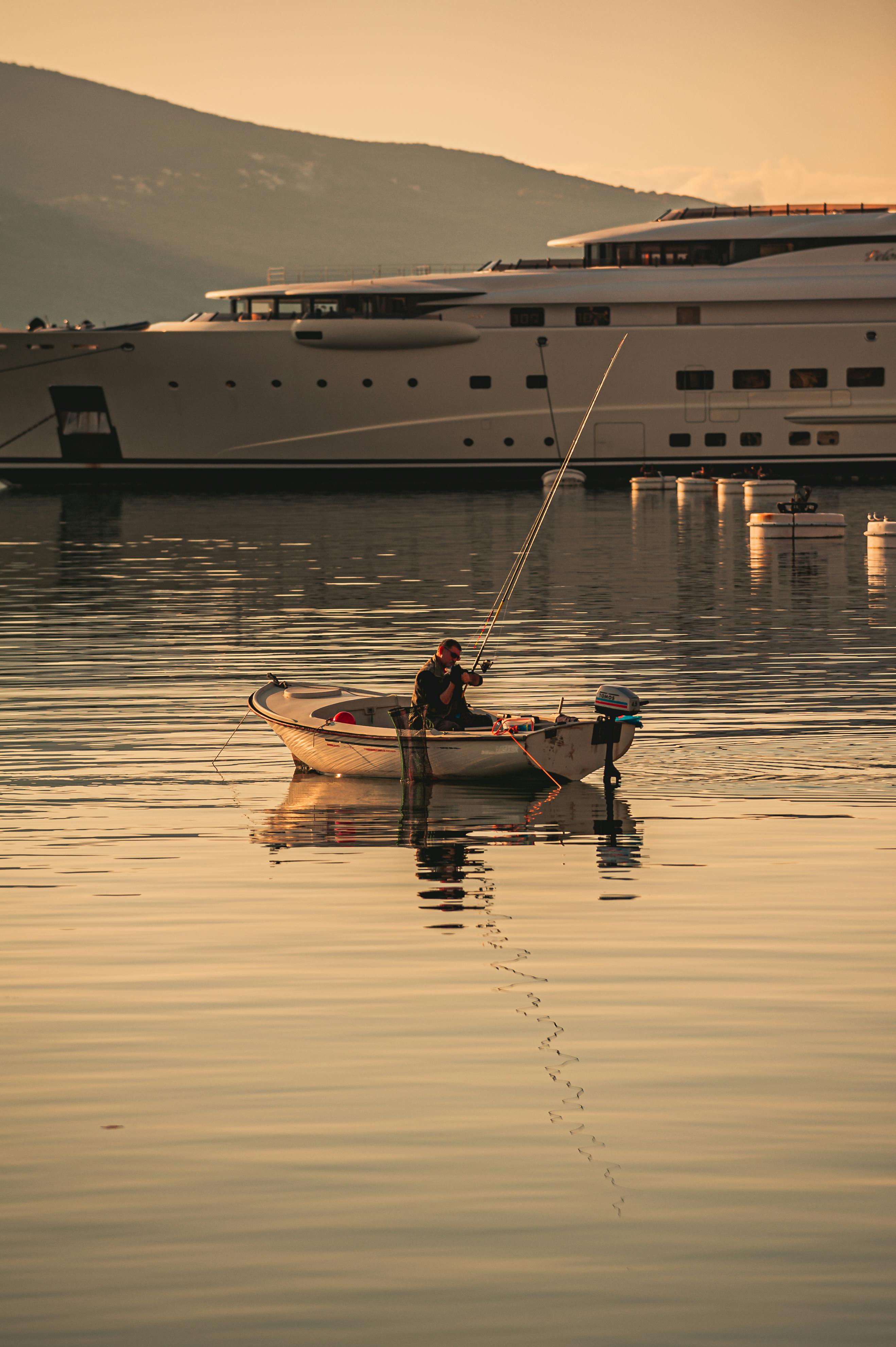 Free Peaceful fishing experience in Tivat with a boat reflecting the calm waters. Stock Photo