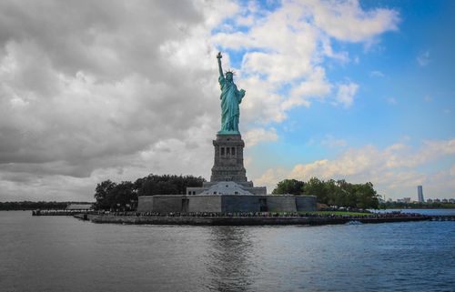 Free A stunning view of the Statue of Liberty against a vibrant sky over New York Harbor. Stock Photo