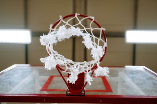 A detailed close-up of a basketball hoop with a frayed net, capturing intensity and vibrant action.