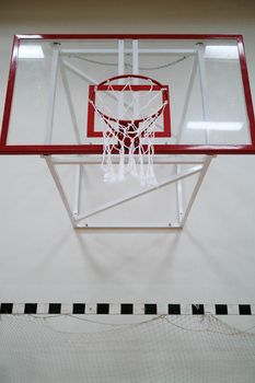 An outdoor basketball hoop and backboard with net, viewed from below on a clear day.