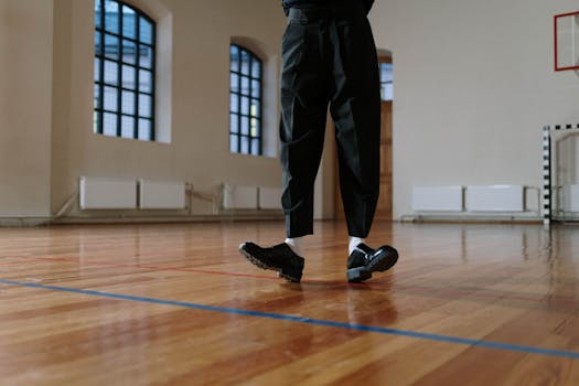Fashionable black leather shoes and black pants on a polished gym floor creating a modern vibe.