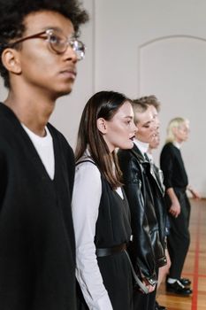 Group of young adults in fashionable clothing standing indoors, showcasing diversity and style.