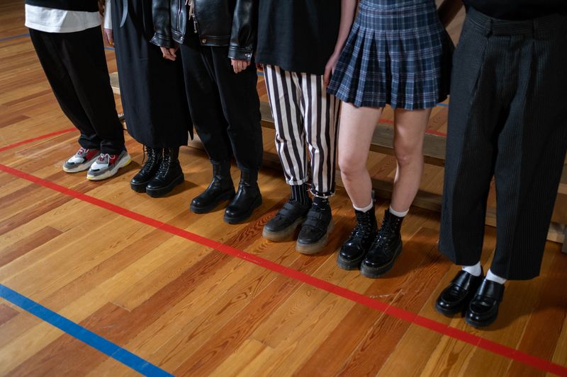 A diverse group showcases stylish footwear on a wooden gym floor, blending fashion and youthful expression