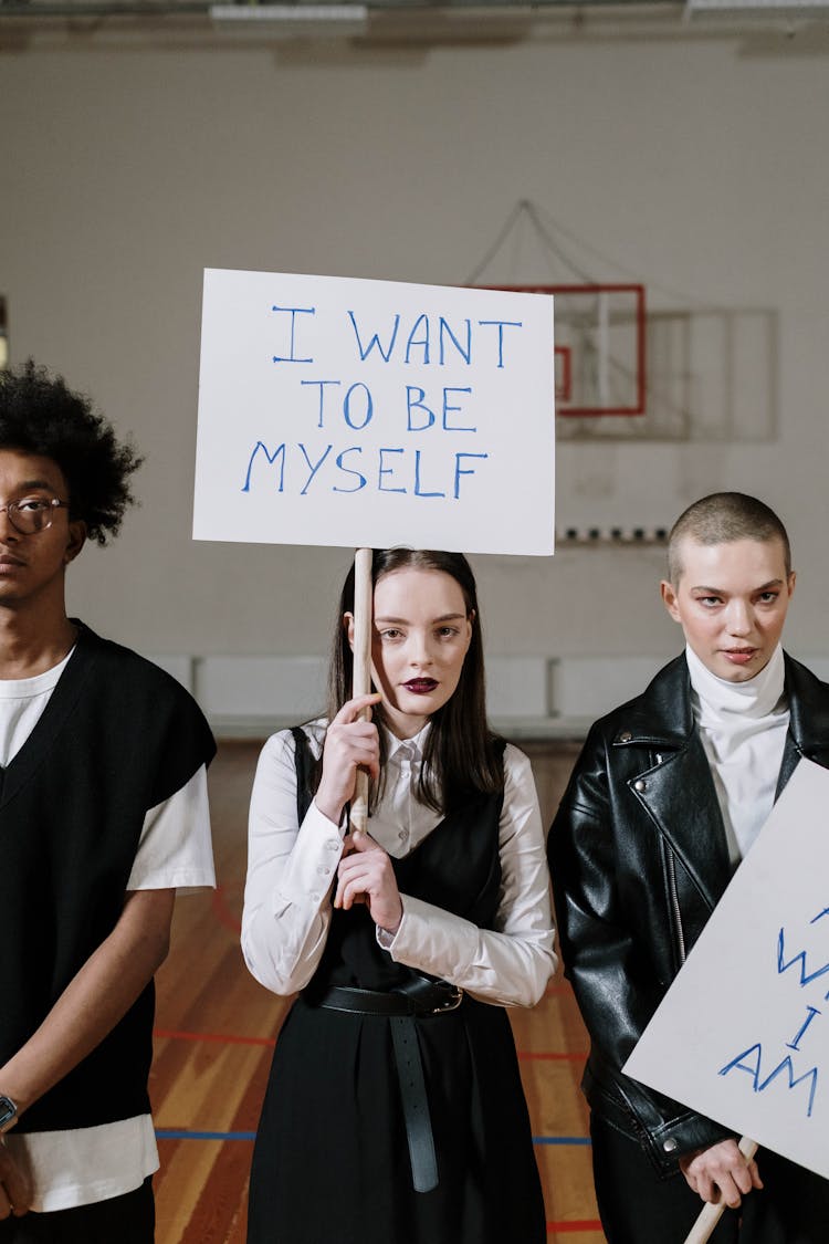 A Group Of Students Standing In The Gym While Holding Placards