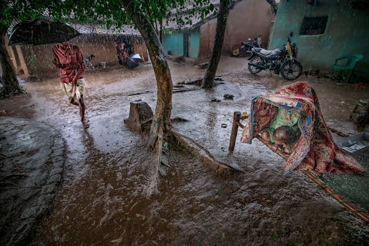 A vibrant scene capturing monsoon rains in a rural village courtyard in Purulia, India.