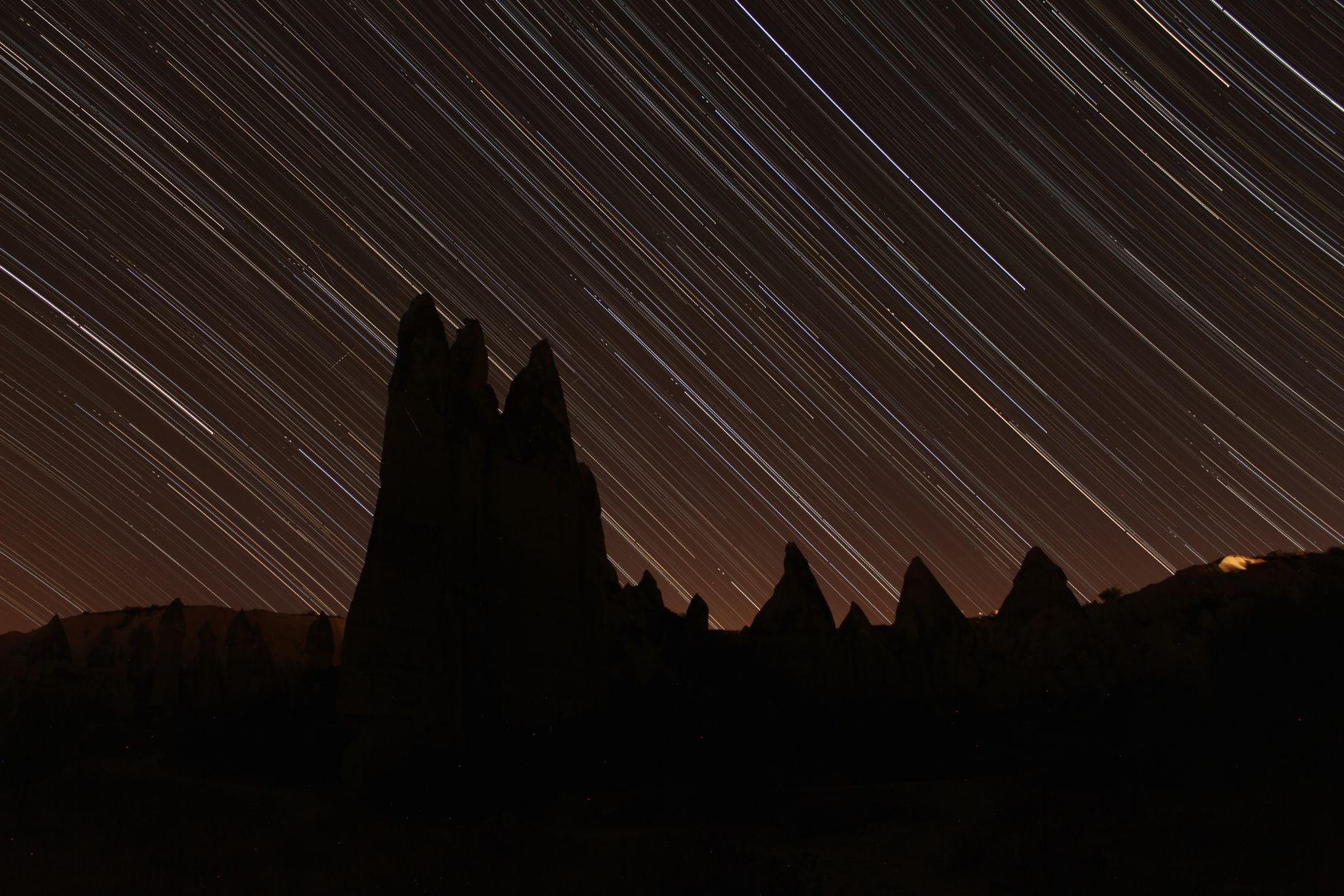 手機延時縮時拍攝技巧:適合新手的場景推薦 Time-lapse photo of star trails above Cappadocia's iconic fairy chimneys at night.