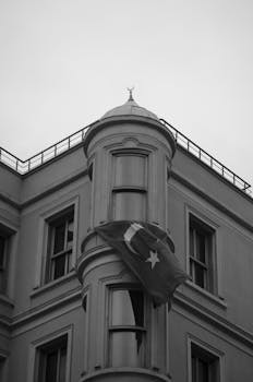 Black and white photo featuring a building with a Turkish flag and classical architecture.