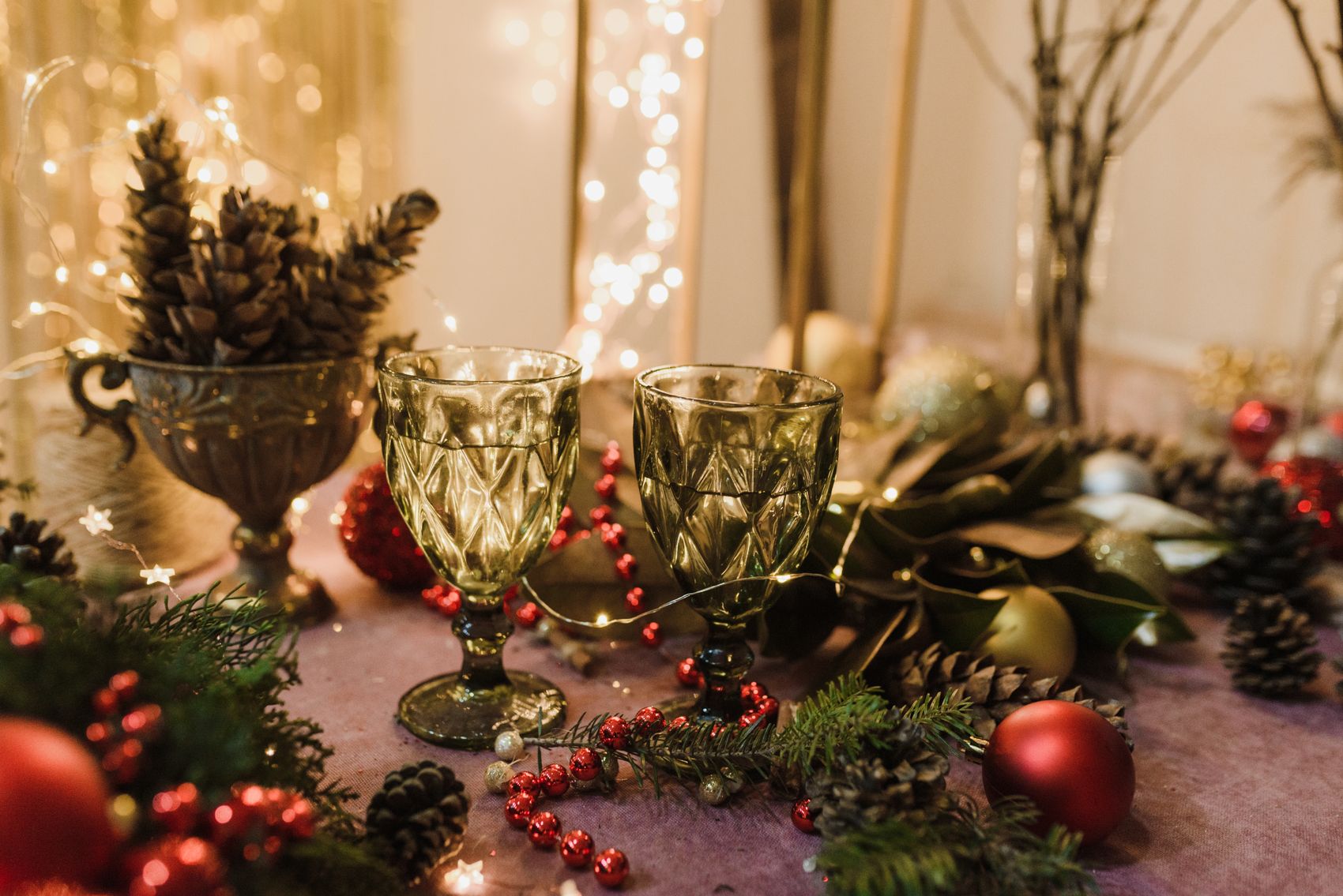 Seasonal holiday table with glassware ornaments greenery and warm lights