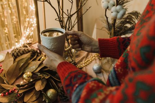 Free Hands holding a mug of hot drink amidst festive holiday decor indoors. Stock Photo
