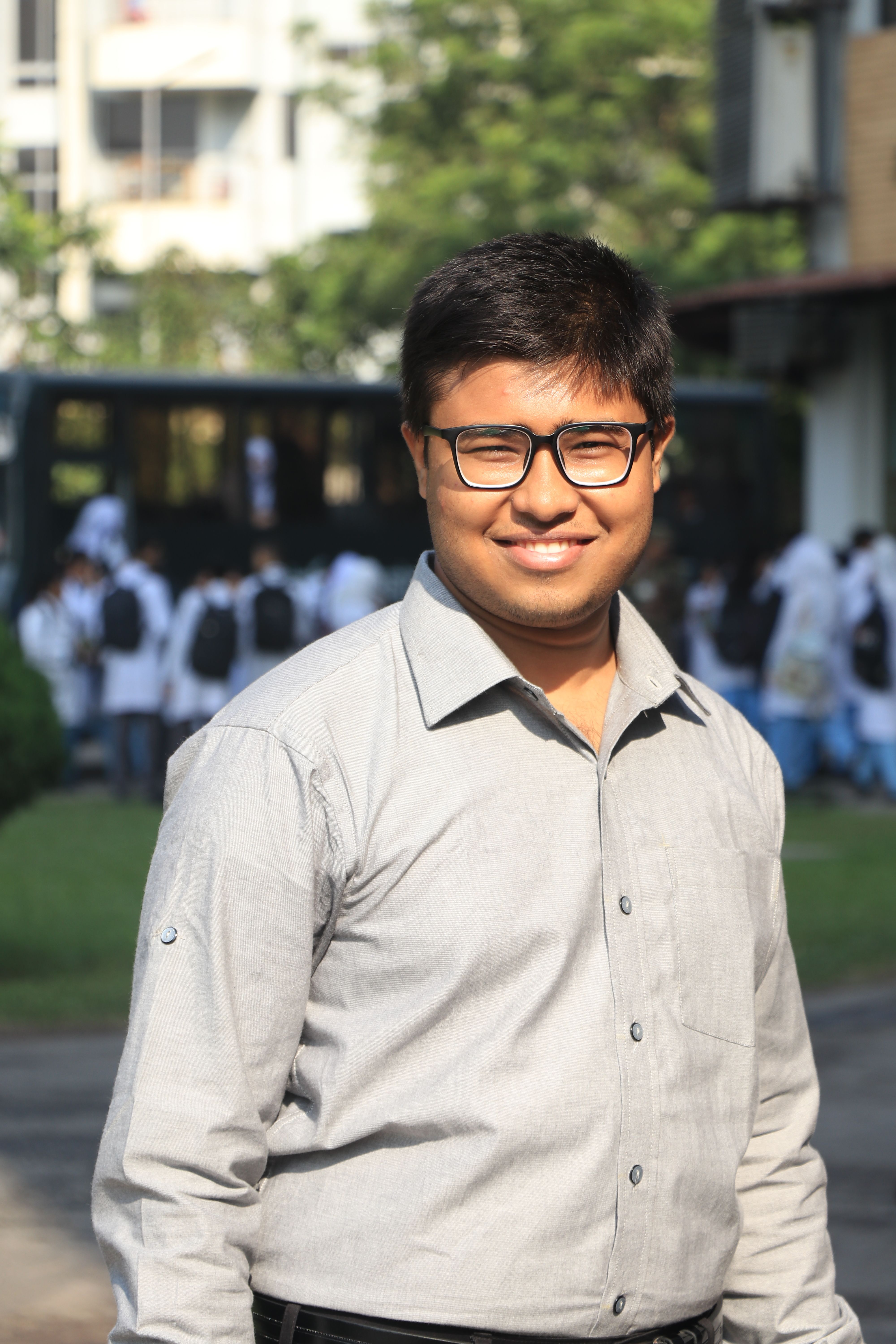 Confident smiling man wearing eyeglasses outdoors in Dhaka, Bangladesh.