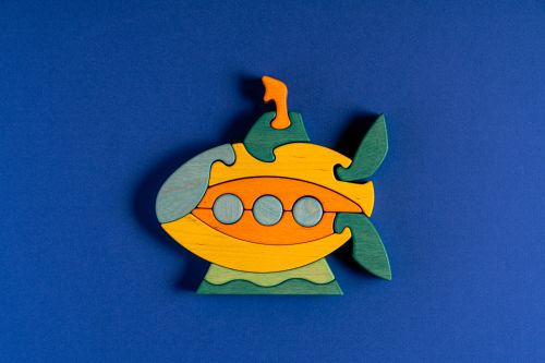 Free Vibrant wooden submarine puzzle on a blue background, playful still life. Stock Photo