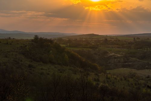 Free Gorgeous sunset casting sunrays over a peaceful rural landscape, perfect for nature and landscape photography enthusiasts. Stock Photo