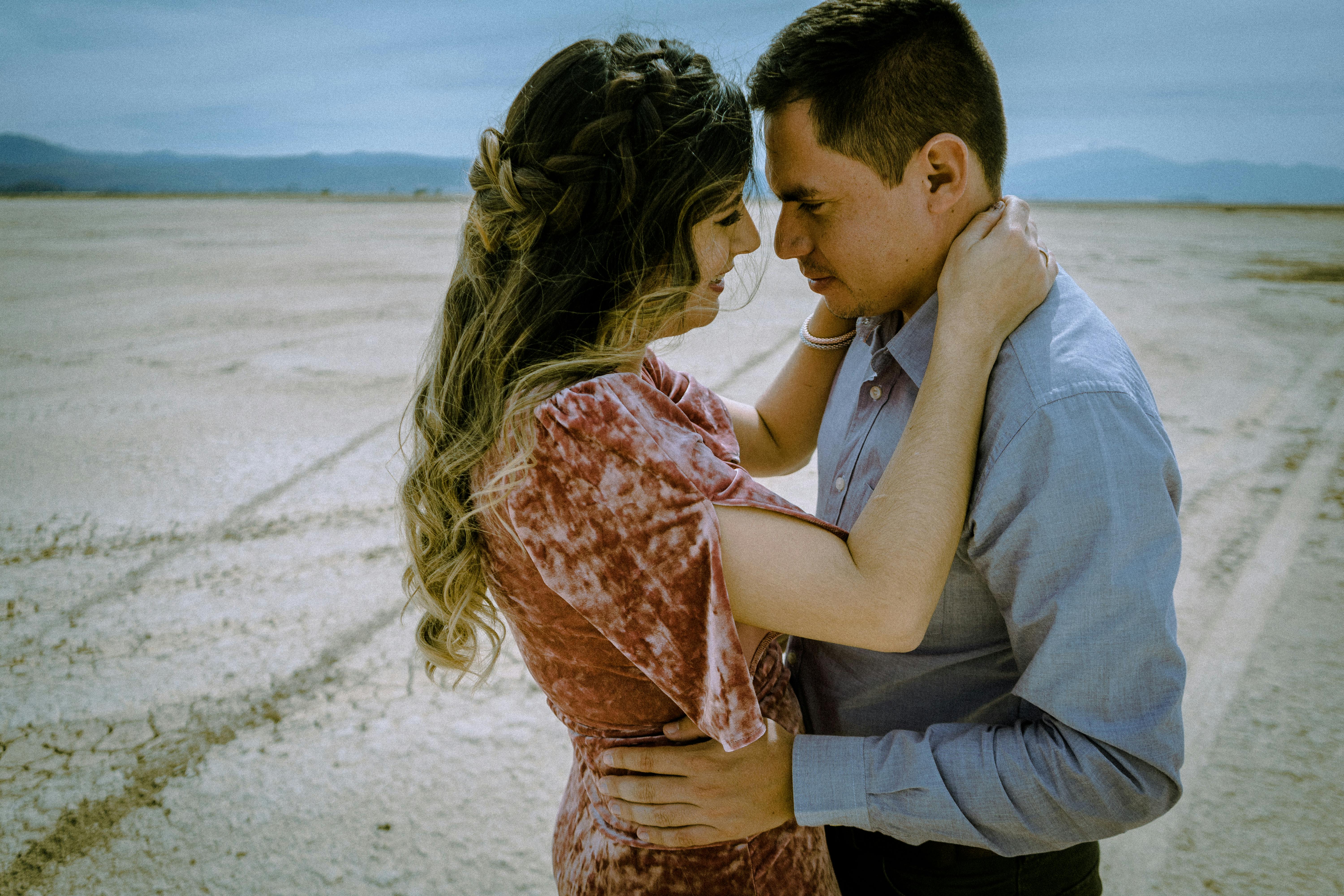 Couple in a loving embrace, face to face in an open desert setting. Captures intimacy.