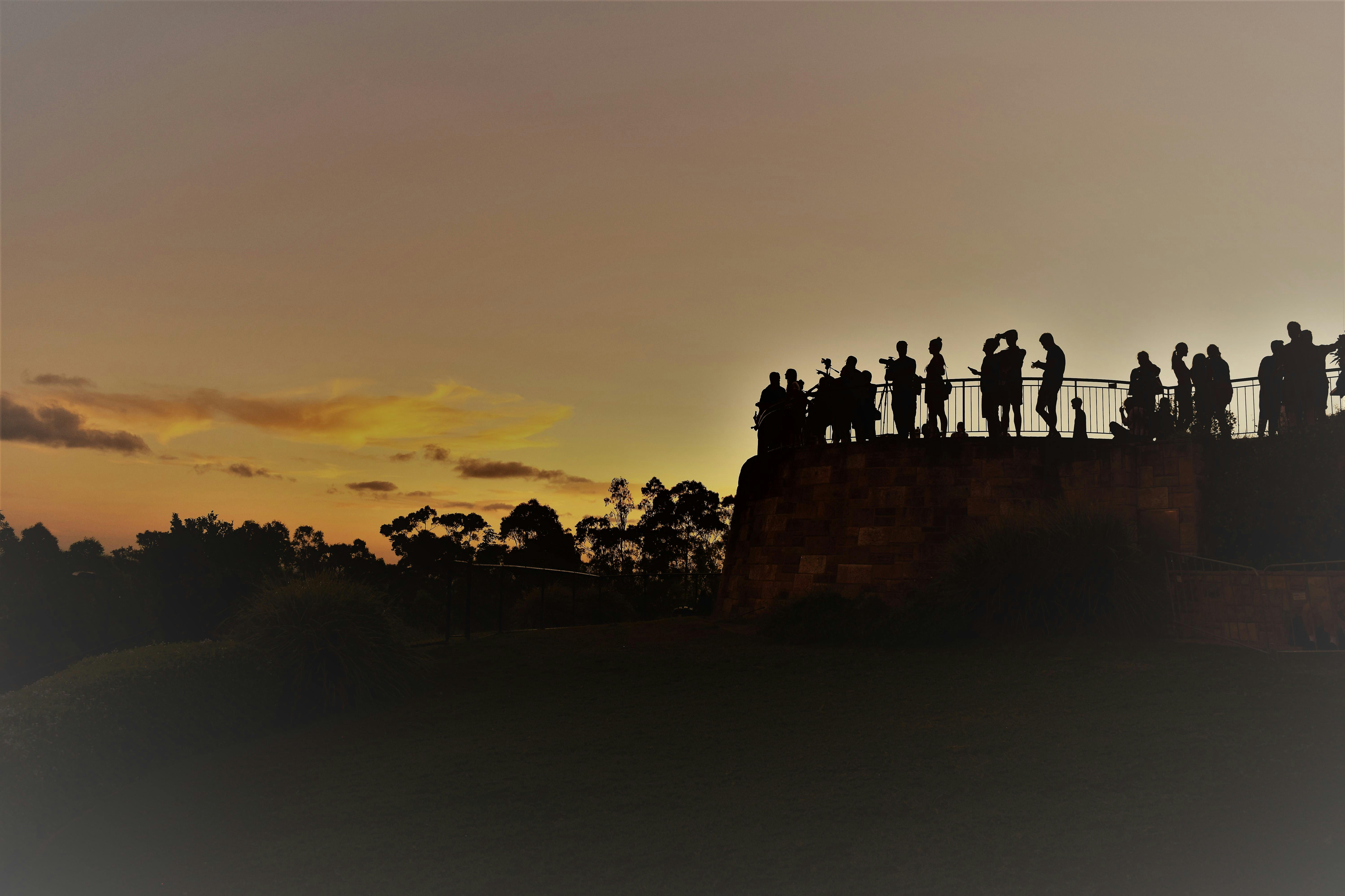 人们在布里斯班天际线上观看充满活力的日落剪影，营造出宁静而风景优美的氛围
