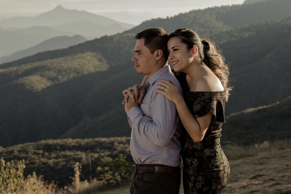 Fotomural Una pareja se abraza amorosamente con un impresionante paisaje montañoso de fondo, evocando el romance.