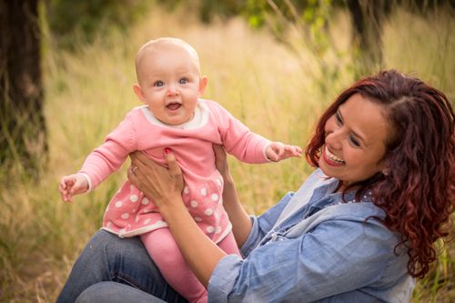 Free Joyful mother and baby girl smiling together outdoors in a sunny nature setting. Stock Photo