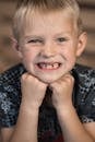 Crop smiling blond boy leaning on hands