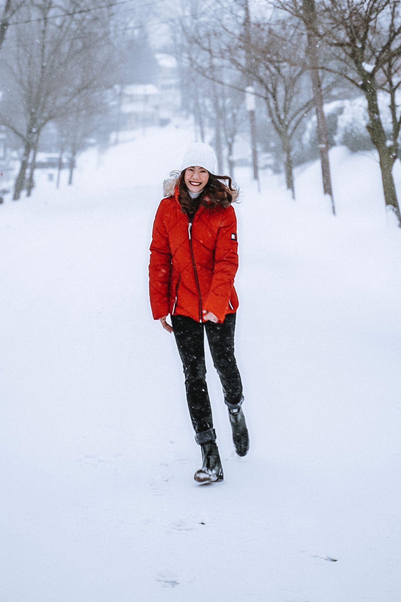 a woman in a red jacket walking through falling snow