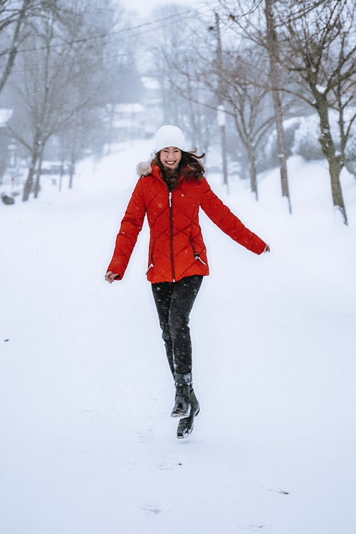 Woman Wearing Red Jacket Jumping on Snow