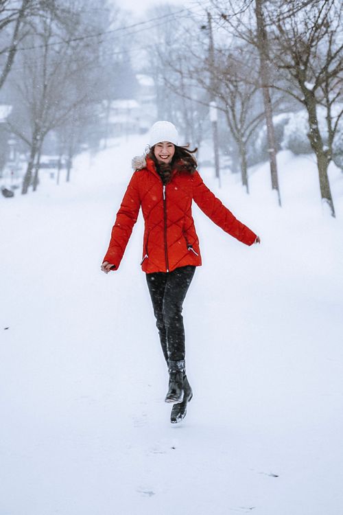 Free Smiling woman in red jacket walking outdoors on a snowy winter day. Stock Photo