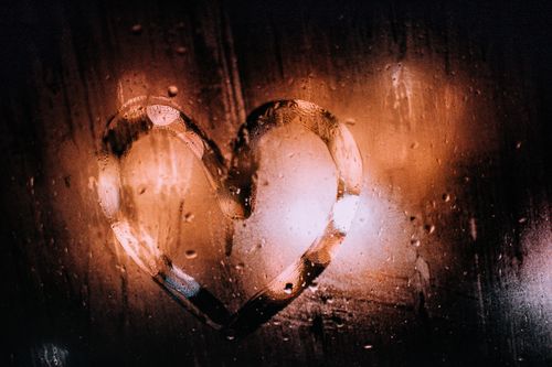 Free A heart shape drawn on a steamy window with warm, bokeh lighting. Stock Photo