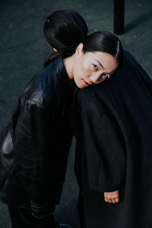 Free An intimate and artistic portrait of two women embracing in dark coats, conveying warmth and connection. Stock Photo