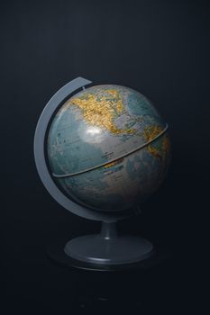 An antique world globe displayed on a dark black background, highlighting North America. 6220536