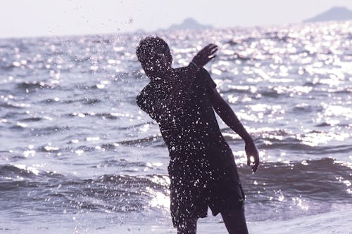 무료 해변에 물이 튀는 남자 스톡 사진
