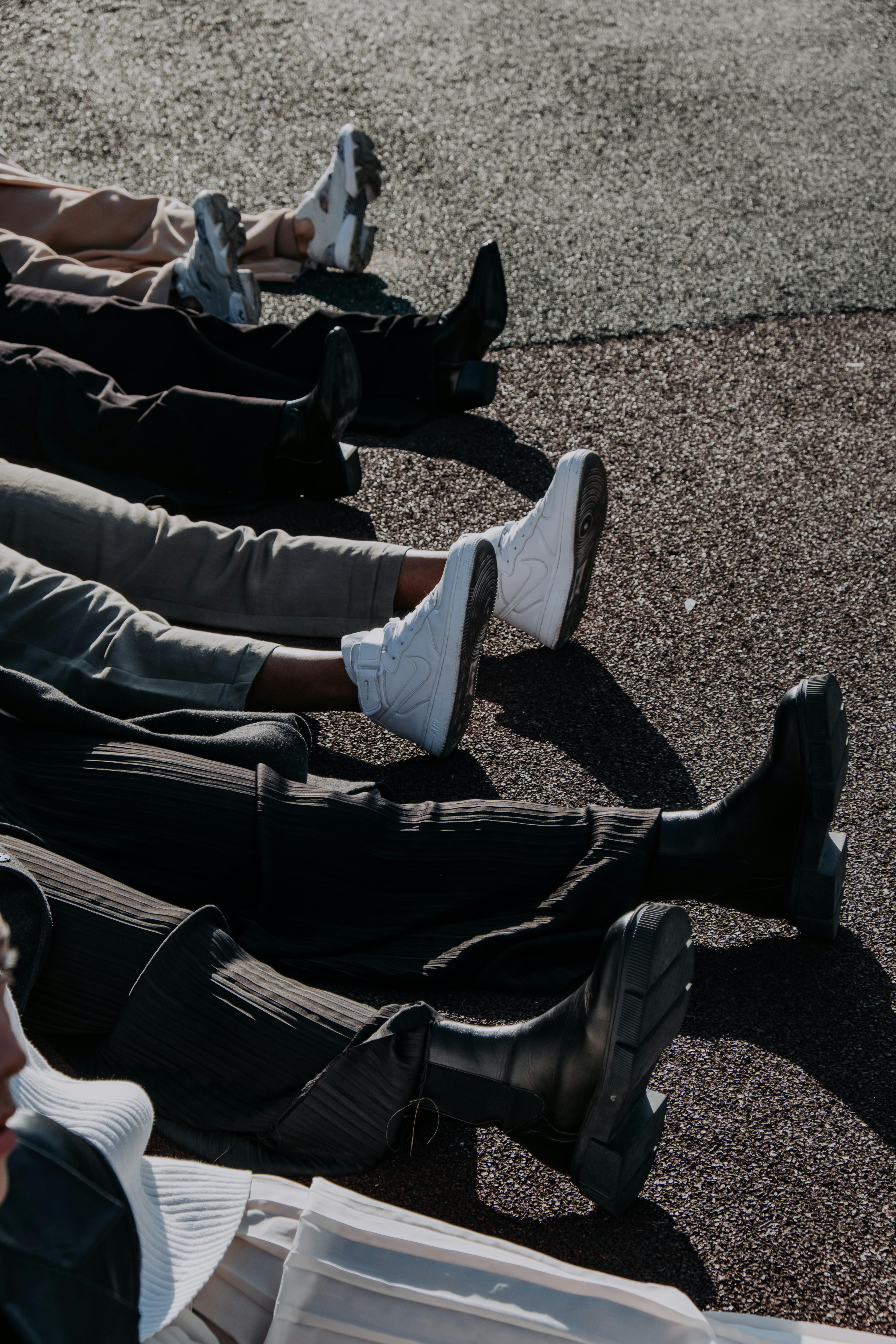 people lying on ground showing different pairs of shoes