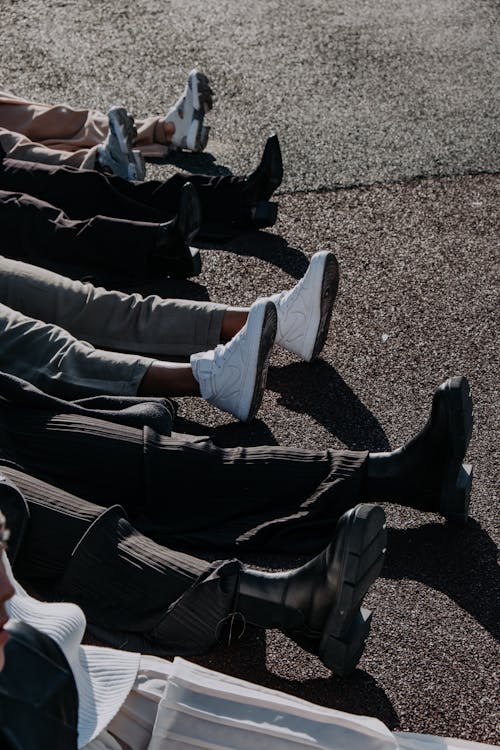 People Lying On Ground Showing Different Pairs of Shoes