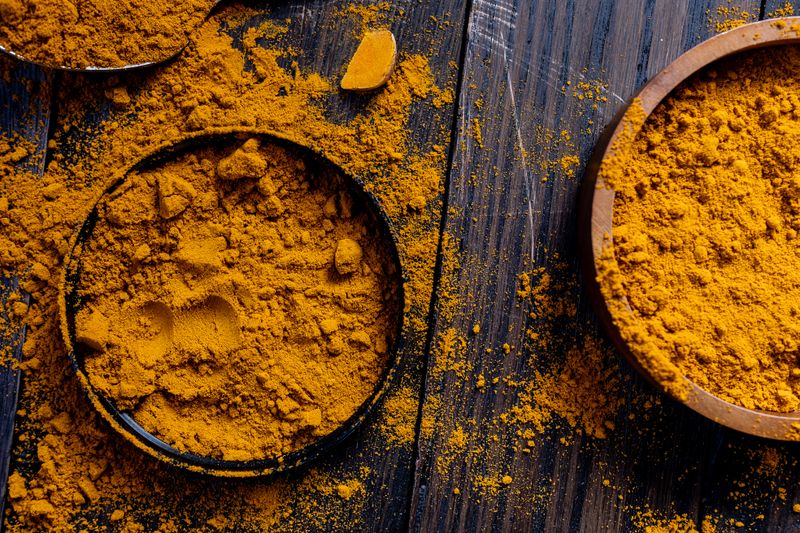 Real close-up photo of turmeric powder in a rustic wooden bowl